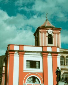 Vertical shot of a baroque church facade with red and white details in Bogotá, Colombia.